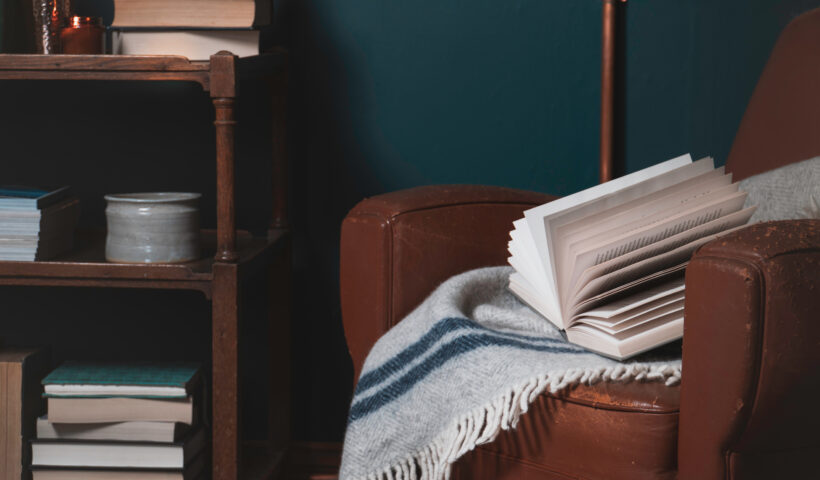 worn brown leather chair, blue wall, bookshelf, books, gray and blue throw blanket decorating tips for small spaces