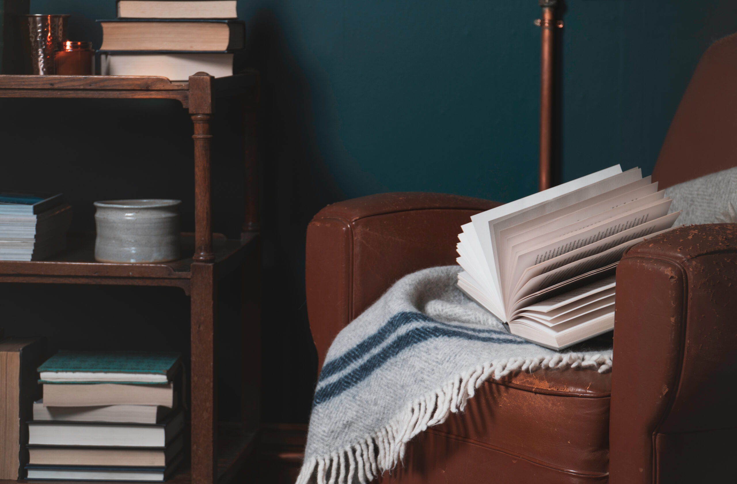 worn brown leather chair, blue wall, bookshelf, books, gray and blue throw blanket decorating tips for small spaces