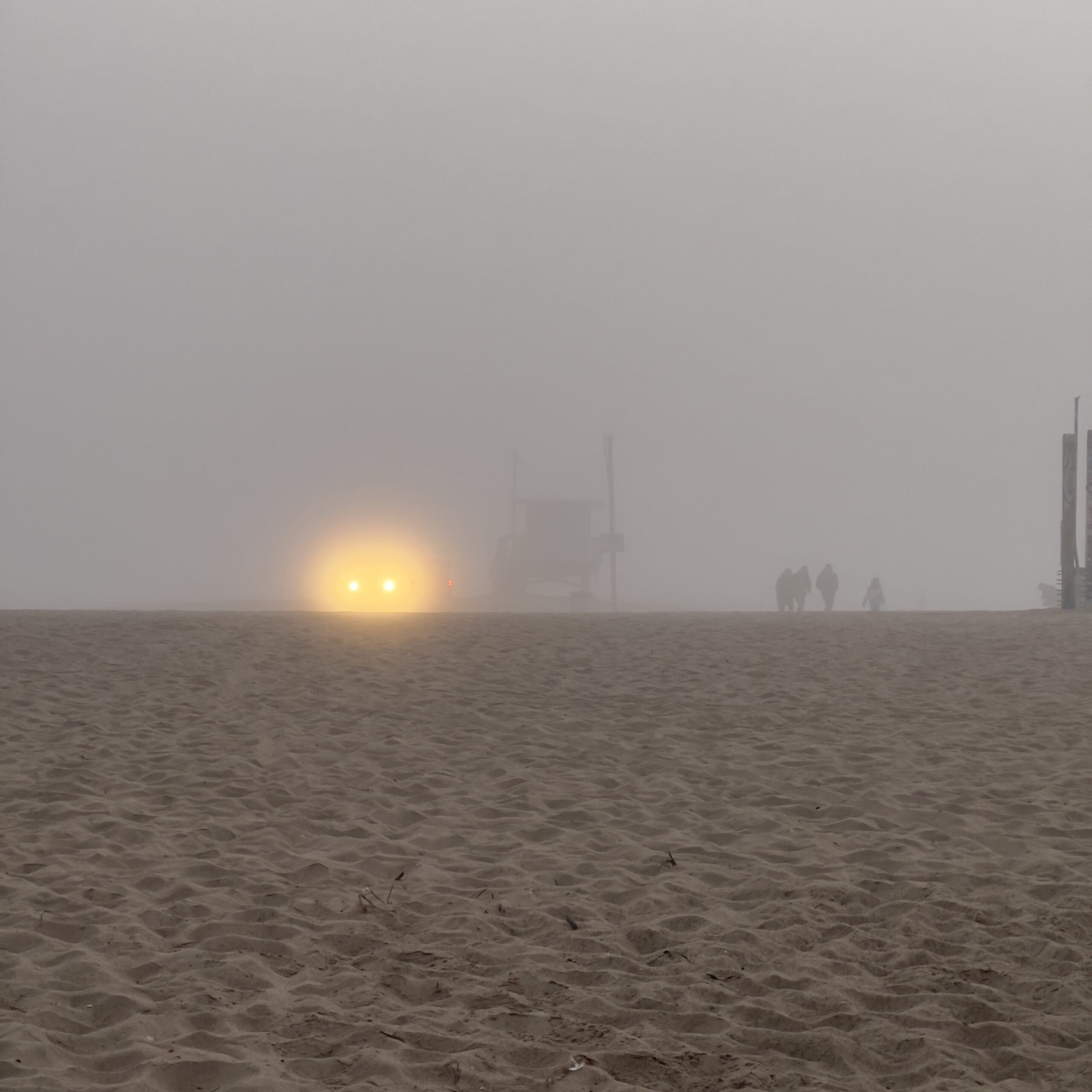 Beach in Fog headlights winter lifeguard shack people walking on sand decluttering emergency kits